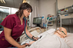 Pueblo Community College nursing student practicing on a medical simulation dummy.