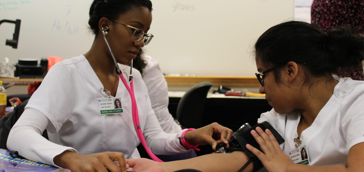 Two POC nursing students practicing taking blood pressure