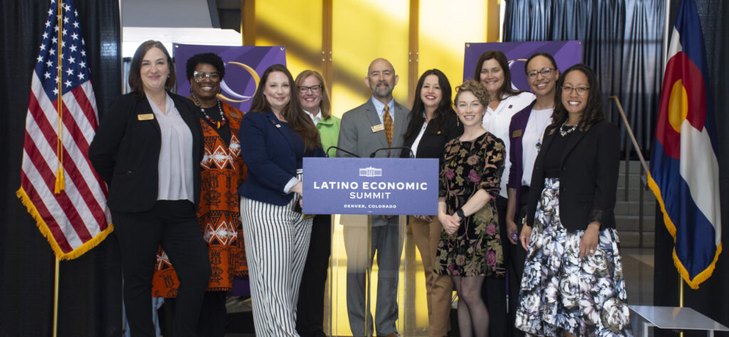 Chancellor Joe Garcia standing on stage of Latino Economic Summit with CCD's leadership team